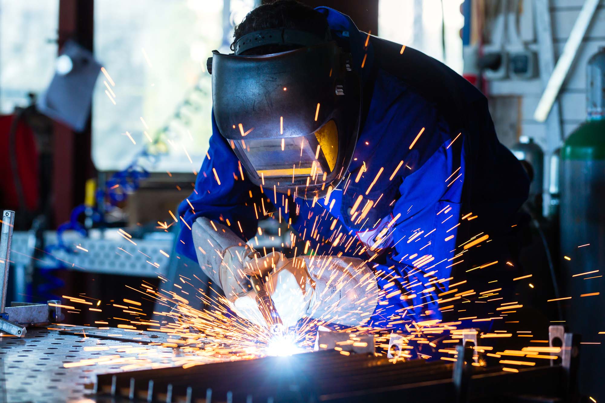 Human working of welding with a lot of sparks in a metal industry factory